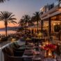 Luksuzna terasa restorana uz plažu u Marbelji pri zalasku sunca, sa palmama, pogledom na more i elegantnom večernjom atmosferom