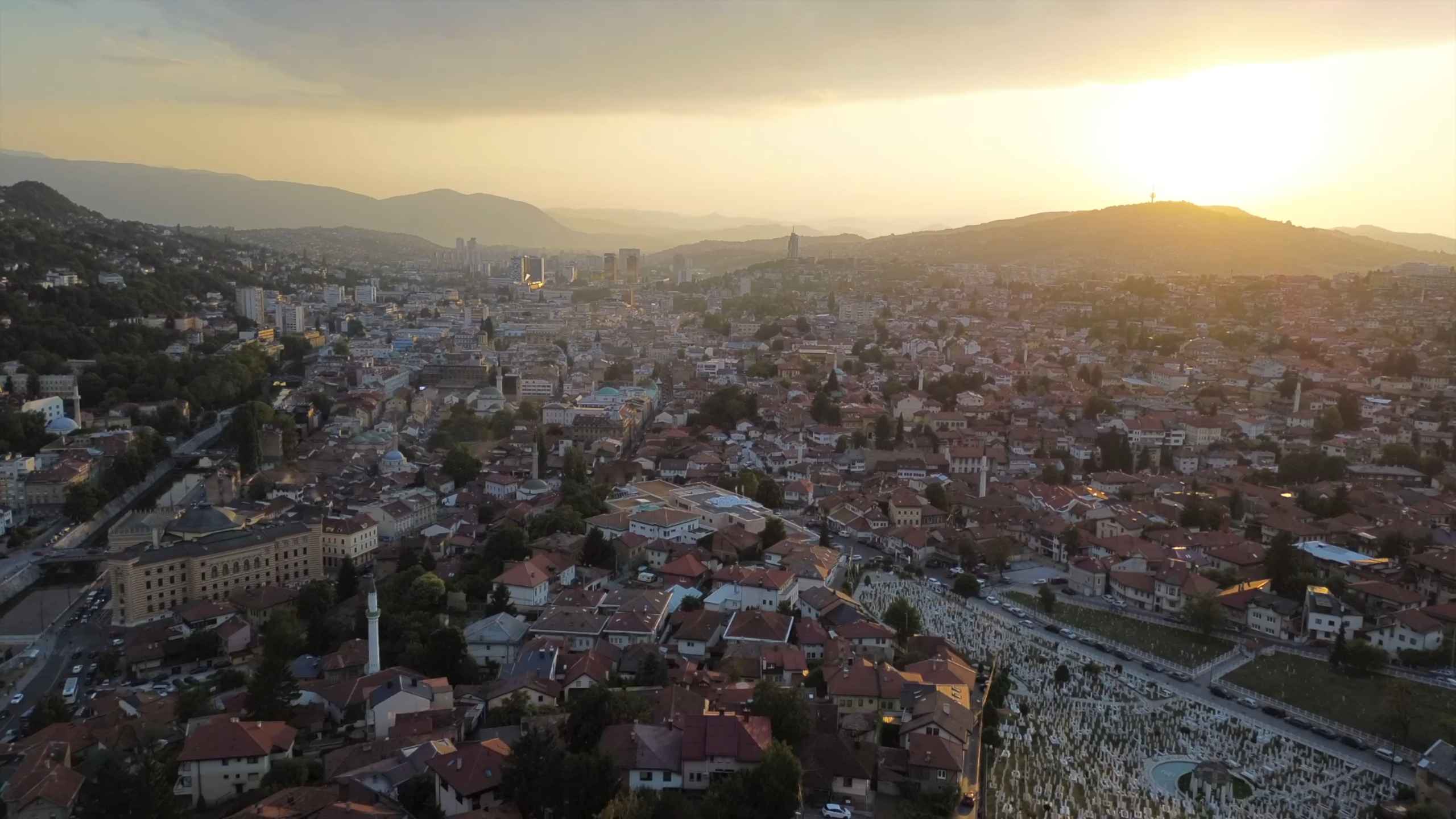 Panoramski pogled na Sarajevo i okolne planine u zalasku sunca.