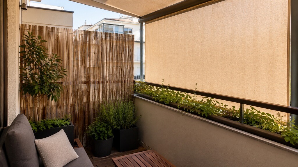 Balkon sa platnenom zaštitom, trščanom ogradom i zelenilom koje pruža privatnost i hladovinu
